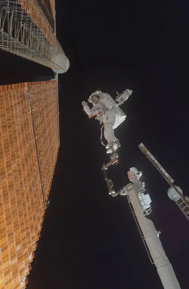 El astronauta Scott Parazynski, sujeto por los pies a uno de los segmentos del brazo robótico CanadaArm, durante la reparación de un panel solar en la Estación Espacial Internacional